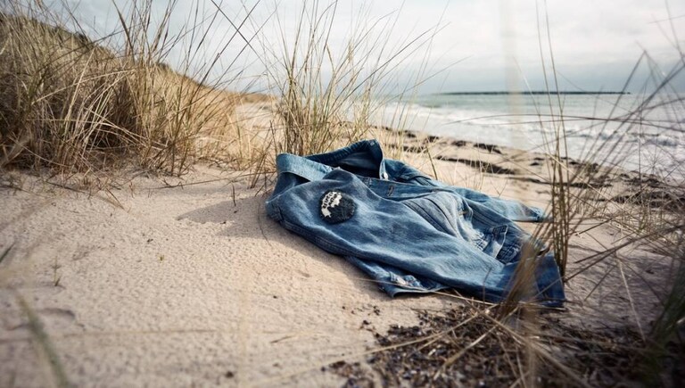 A jeans jacket lying on the beach representing environmentally-friendly living