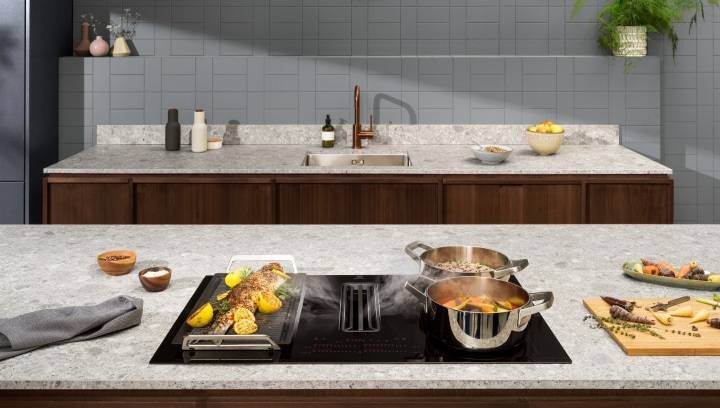 Food cooking on a hob using different cooking zones. Built-in extractor rids the air of odours and steam 